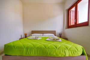 a bedroom with a green bed with two towels at SanvitoTour - Appartamenti Il Mulino in San Vito lo Capo