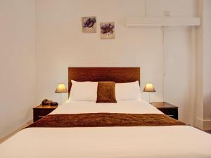 a bedroom with a large white bed with two lamps at The Waverley Hotel in Great Yarmouth
