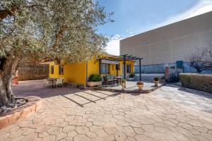 a courtyard with a yellow building and a tree at Cortijo Ginatar in Dúrcal