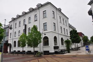 um grande edifício branco numa rua da cidade em Hotel Phønix Brønderslev em Bronderslev