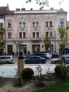 un edificio rosa con macchine parcheggiate di fronte di Palace Bulevard Inn a Cluj-Napoca