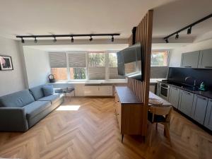 a living room with a blue couch and a kitchen at Apartamentai KOPOS Nidoje in Nida