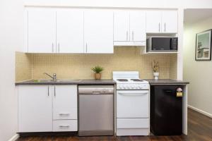 a kitchen with white cabinets and a white stove top oven at Darling Harbour Studio w Pool Sauna Gym Jacuzzi in Sydney