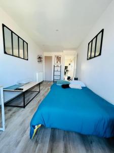 a bedroom with a blue bed and a desk at Le Belvédère Dernier étage avec terrasse WIFI FIBRE in Tarbes