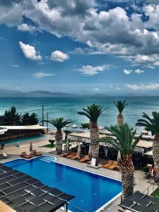une piscine avec des palmiers et l'océan en arrière-plan dans l'établissement Evvoiki Akti Hotel, à Politiká