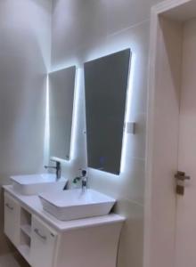 uma casa de banho branca com 2 lavatórios e um espelho em شاليه هابي نايت em Al Harazat
