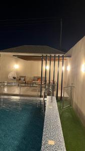 uma piscina à noite com uma casa em شاليه هابي نايت em Al Harazat