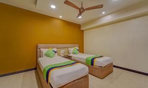 a bedroom with two beds and a ceiling fan at Treebo Elan in Chennai