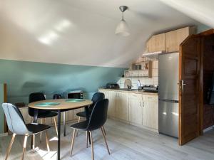 een keuken met een tafel en stoelen en een koelkast bij Apartament Nad Suwalskim Bulwarem in Suwałki