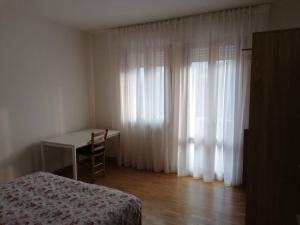 a bedroom with a desk and a table and curtains at casa a due passi dal centro in Padova