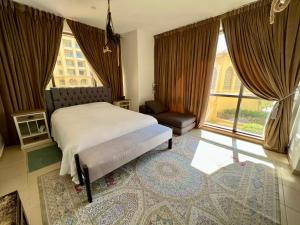 a bedroom with a bed and a chair and windows at Amazing and spacious apartment in JBR in Dubai