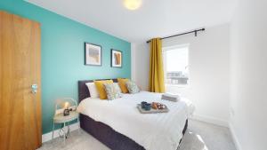 Schlafzimmer mit einem Bett mit blauer Wand in der Unterkunft Water View Apartment- 2 Bed - Cardiff Bay - Free Parking!! in Cardiff