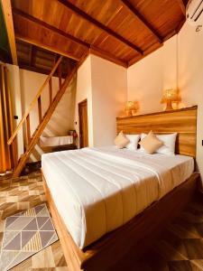 a bedroom with a large white bed with wooden ceilings at Turtle Wood Cabin in Tangalle