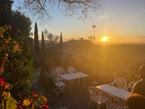 einen Sonnenuntergang in einem Garten mit Tischen und Stühlen in der Unterkunft Auberge Prieuré du Vieux Fox in Fox-Amphoux