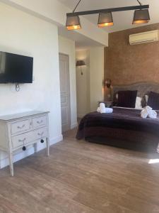 1 dormitorio con 1 cama, TV y vestidor en Hôtel de La Fossette en Le Lavandou