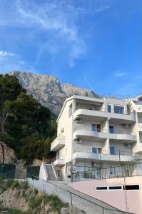 a white apartment building with mountains in the background at Apartments Ćorić in Baška Voda