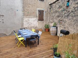 una mesa y sillas en una terraza de madera en Maison la vague, en Meyrueis