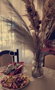 a table with a plate of food and a vase of flowers at Apartment Vila Tara in Bihać