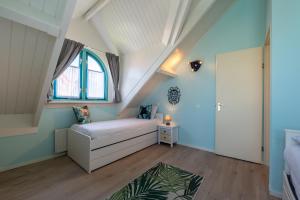Cette chambre mansardée comprend un lit et une fenêtre. dans l'établissement Bandol 184 - Kustpark Village Scaldia, à Hoofdplaat