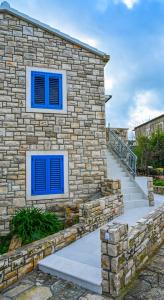 Casa de piedra con ventanas azules y escaleras en Apartment Leo Blue, en Vela Luka