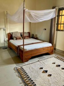 1 dormitorio con cama con dosel y alfombra en Porto-Novo logement lumineux et calme en Porto-Novo