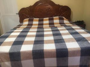 a bed with a blue and white checkered blanket at Kalsa Residence in Sukuta