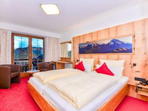 ein Schlafzimmer mit einem großen Bett mit roten Kissen in der Unterkunft Alpenhotel Denninglehen in Berchtesgaden