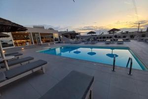 a large swimming pool with chairs and umbrellas at En Plo Boutique Suites in Oia