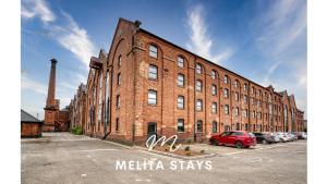 a brick building with a red car parked in a parking lot at Modern 1 bedroom apartment in Burton upon Trent