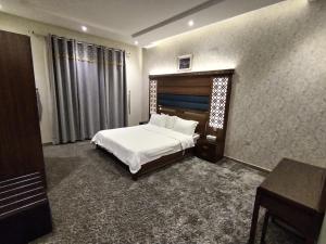 1 dormitorio con cama blanca, mesa y escritorio en امارلس للشقق الفندقية en Khamis Mushayt