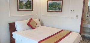 een slaapkamer met een wit bed met twee foto's aan de muur bij Tam Cốc Anna Thắm Hotel in Ninh Binh