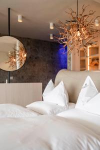a bedroom with two beds with white sheets and a chandelier at Hotel Mitterplatt (Schenna Resort) in Schenna