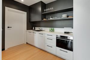 eine Küche mit weißen Schränken und einer schwarzen Wand in der Unterkunft Luxury Aura 40 - 2 by Grand Apartments in Danzig