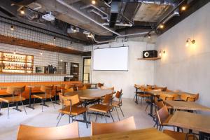 a dining room with tables and chairs and a whiteboard at Agora Place Tokyo Asakusa in Tokyo