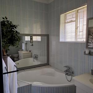 a bathroom with a bath tub with a large mirror at Pandora's Guest Lodge in Klerksdorp