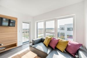 sala de estar con sofá gris y almohadas coloridas en Appartements Thermen-Golfresort Pannonia, en Zsira