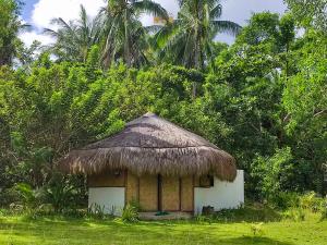 a small hut with a thatched roof in a field at Playa Paraiso Nagtabon Beach in Bacungan