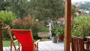 una terraza con una silla roja y un jardín de flores en Freyung, Ferienwohnung Sonnenschein en Schönberg
