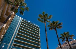 een hoog gebouw met palmbomen ervoor bij Leonardo Hotel Fuengirola Costa del Sol in Fuengirola