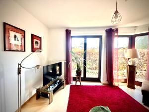 a living room with a television and a red rug at FeWo Rajek -Alte Salzstraße 14- in Pogeez