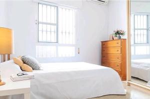 a white bedroom with a large bed and a dresser at Los Duendes in Almería