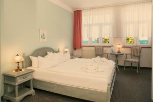 a hotel room with a large white bed and two chairs at Hotel Esplanade Garni in Kühlungsborn