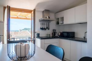 una cocina con armarios blancos y una mesa con sillas. en Belvedere - Terrazza panoramica en Bosa