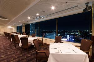 ein Restaurant mit Tischen und Stühlen und Stadtblick in der Unterkunft Hotel Agora Osaka Moriguchi in Osaka