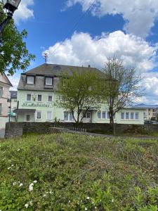 Una casa blanca con un árbol delante. en Hotel St. Hubertus en Wallmerod