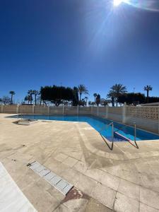 ein leerer Swimmingpool mit Zaun und Palmen in der Unterkunft Apartamento 2 habitaciones frontal al mar 2 in Torre del Mar