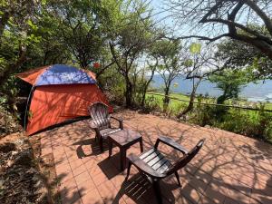 two chairs and a tent on a brick patio at Advait Valley Camp, Kshetra Mahabaleshwar in Mahabaleshwar