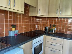 a kitchen with white cabinets and black counter tops at Villa in Youghal - Carleton Village in Youghal