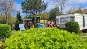 an rv and a playground in a yard at Domki Letniskowe BURSZTYNEK in Jarosławiec