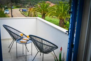 uma varanda com duas cadeiras e uma mesa com comida em Apartment Leo Blue em Vela Luka